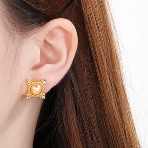 Close-up of vintage 18K gold-plated shell pearl stud earrings with crystal accents