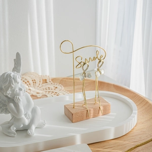 Elegant gold tassel earrings with bow elements and pearls on a vintage angel stand