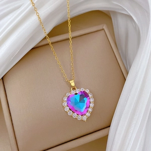 Detailed macro view of gold heart necklace with iridescent gemstone and crystal accents