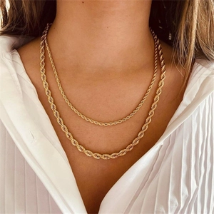 Detalle de cadenas de cuerda superpuestas de acero inoxidable bañadas en oro sobre modelo