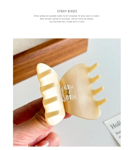 Detail showing creamy acetate hair claw clip with golden spring and glossy finish