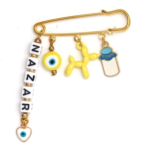 Detail of gold safety pin brooch with NAZAR beads, evil eye and balloon dog pendants