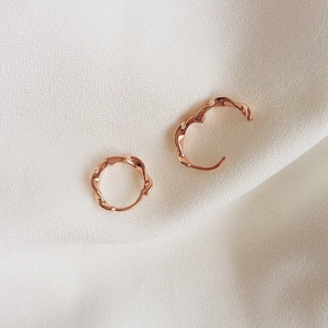 Close-up of rose gold twisted hoop earrings showing the flexible opening mechanism