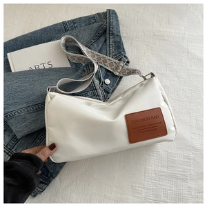 Detail of white nylon crossbody bag featuring a wide geometric pattern strap and leather patch