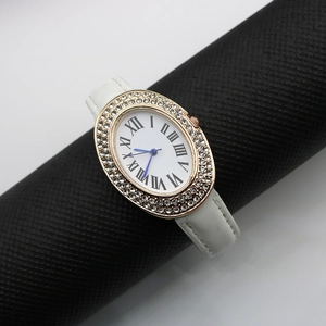 Macro view of oval gold watch case with crystal bezel and Roman numerals on white dial