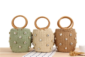 Detailed view of woven straw bucket bags with round wooden handles and sparkling rhinestones
