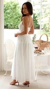 Robe longue blanche élégante avec jupe à volants et design ajouré dans un cadre de vacances