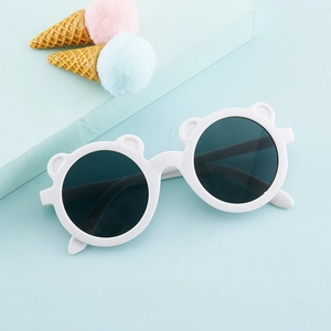 Close-up of white round bear-ear sunglasses for kids with dark lenses on a blue background