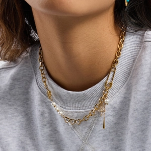 Collier chaîne trombone dorée avec perle cœur et pendentif croix porté par un mannequin