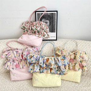 Dettaglio borse shopper in tela con volant floreali nei colori rosa, giallo e blu
