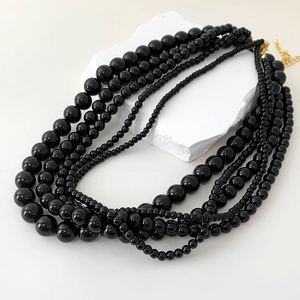 Elegant multi-layer necklace with black onyx beads and gold clasp on white stone decor