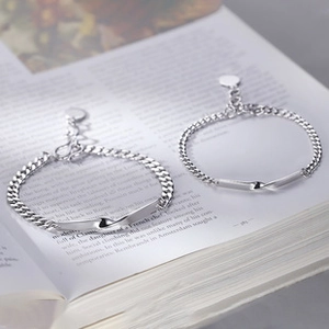 Detail of silver Cuban chain bracelets with heart pendant and twisted metal design