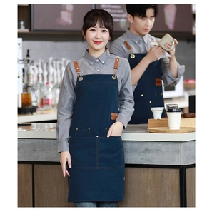Detail of dark blue canvas apron with brown leather straps and multi-pocket design