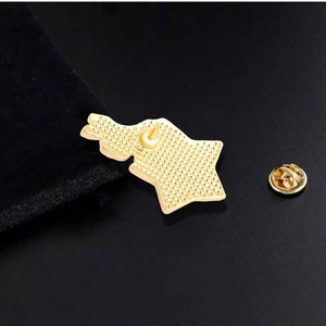 Star shaped gold metal brooch with flame details and butterfly clutch on dark background