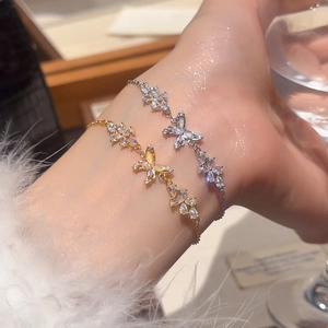 Detail of 18k gold and silver plated bracelets with zircon butterfly and flower charms