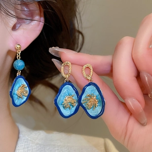 Vue détaillée de boucles d'oreilles vintage avec émail bleu et détails de corail dorés