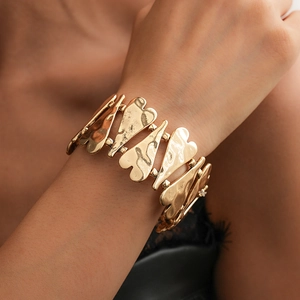 Détail d'un large bracelet doré à maillons en forme de cœur avec texture métallique martelée