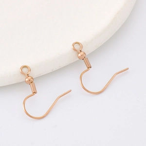 Rose gold stainless steel earring hooks with spring coil detail on a white ceramic plate