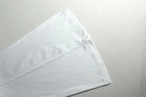 Close-up of white knitted fabric detail showing clean stitching and smooth hem texture