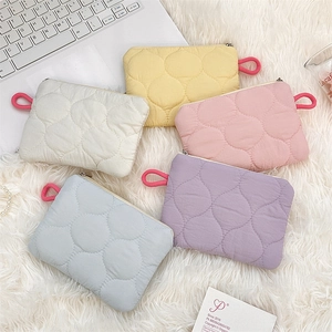 Quilted macaron zipper pouches in beige, yellow, pink, blue, and purple on plush mat