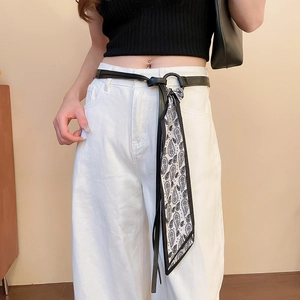 Detail of slim black leather belt with a paisley silk scarf fringe decoration for women