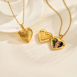 Macro shot of an openable heart locket necklace in gold with floral engraving and photo