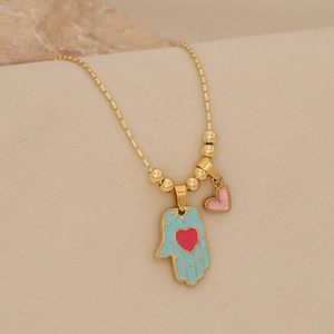 Macro shot of gold Hamsa Hand necklace with blue enamel and pink heart detail