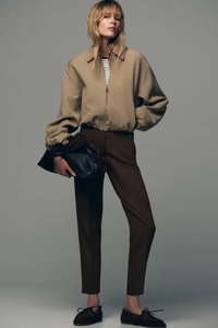 Gros plan sur une veste courte zippée kaki pour femme avec haut rayé et pantalon marron