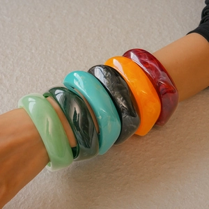 Close-up of stacked colorful resin bangles with marble texture on female wrist