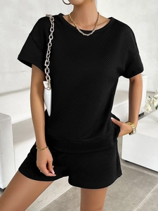 Detail of black knit two-piece set featuring textured diamond and diagonal weave patterns