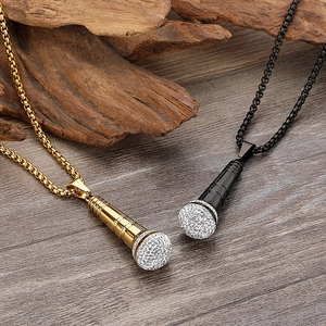 Detailed view of gold and black microphone pendants with crystals on a wooden surface