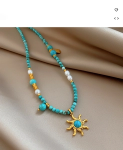 Détail d'un collier en perles avec turquoise, perles et pendentif soleil doré