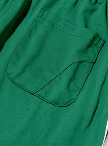 Macro shot of the green jogger pants showing the curved pocket seam and fabric texture
