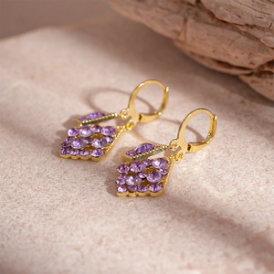 Close-up of vintage geometric diamond earrings with purple crystals on a stone surface
