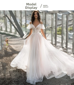 Detail of off-shoulder lace wedding dress with V-neck and sparkling sequins on tulle