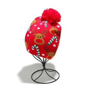 Close-up of a festive red knit beanie featuring reindeer, candy cane, and snowflake patterns