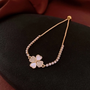 Detailed view of 18k gold plated clover bracelet with mother of pearl on black texture
