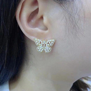 Close-up of elegant 18K gold plated butterfly earrings with micro-set pearls on model