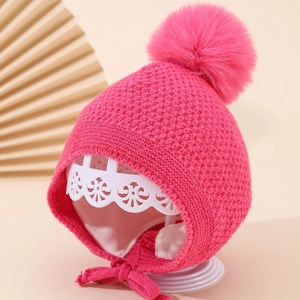 Detail der warmen pinkfarbenen Strickmütze für Kinder mit Bommel und Innenfutter