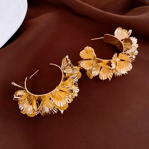 Détail de boucles d'oreilles dorées feuilles de ginkgo avec texture métal sur velours