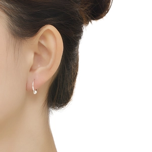 Detailed close-up of s999 sterling silver hoop earring with a small metal bead on ear