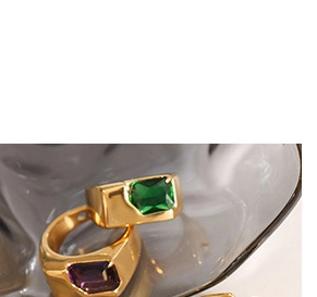 Close-up of gold signet rings featuring rectangular emerald green and purple gemstones