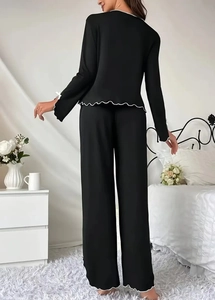 Detail of black pajama set with white lettuce edge trim on sleeves and pant hem