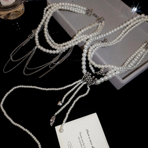 Détail du collier de perles multicouche avec chaînes argentées et pendentifs élégants