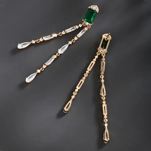 Macro detail of vintage emerald drop earrings with emerald-cut gems and gold tassels