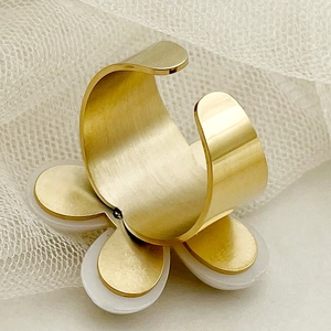 Macro shot of gold brushed open ring with multi-layered white and gold flower petals