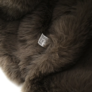 Macro detail of dark brown faux fur texture and 100% polyester care label on winter hat
