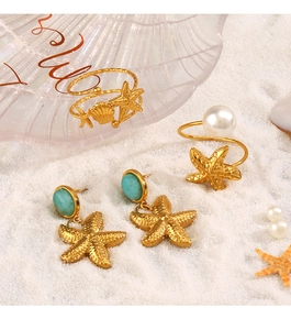 Set gioielli stella marina dorata con perle e turchese su una spiaggia bianca