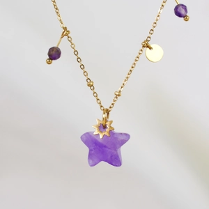 Close-up of golden necklace with purple star pendant and small bead charms