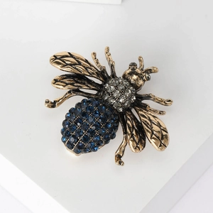 Close-up of vintage bronze bee brooch with deep blue rhinestones on white background